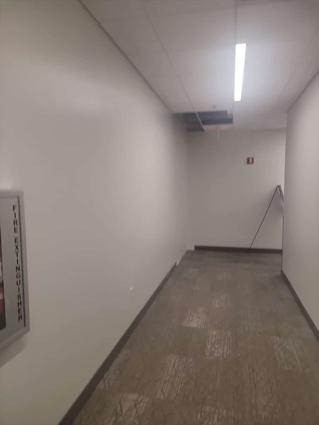 Finished white corridor with carpet tile flooring and a fire extinguisher cabinet.