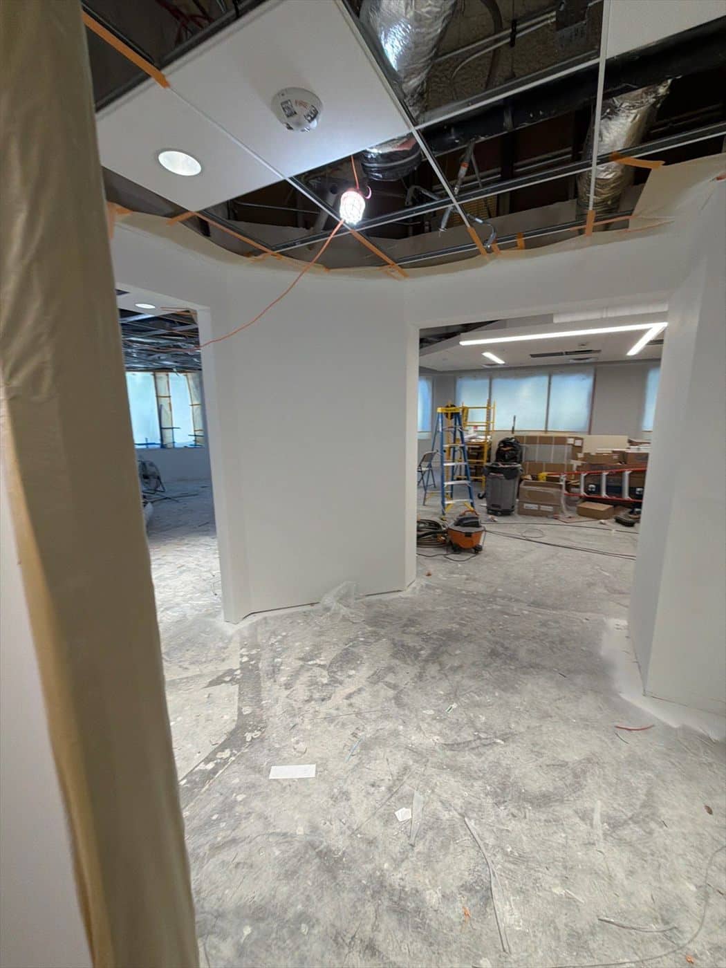 Interior corridor and open space with partial ceiling and staged work areas.