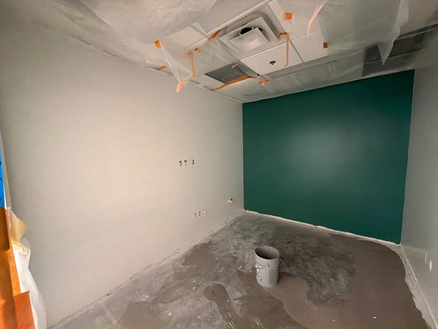 Small office with a freshly painted dark green accent wall and white walls.