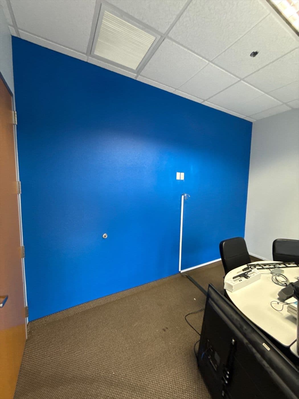 Freshly painted blue accent wall in a small office with desk and chairs.