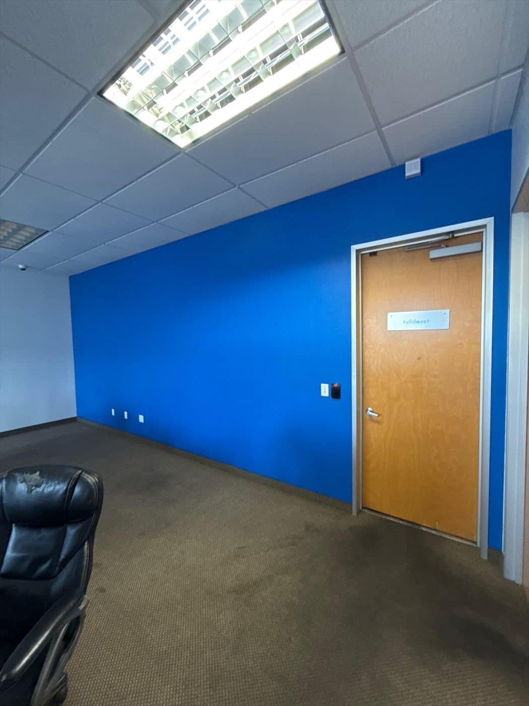 Office room with a completed blue accent wall and wood door.