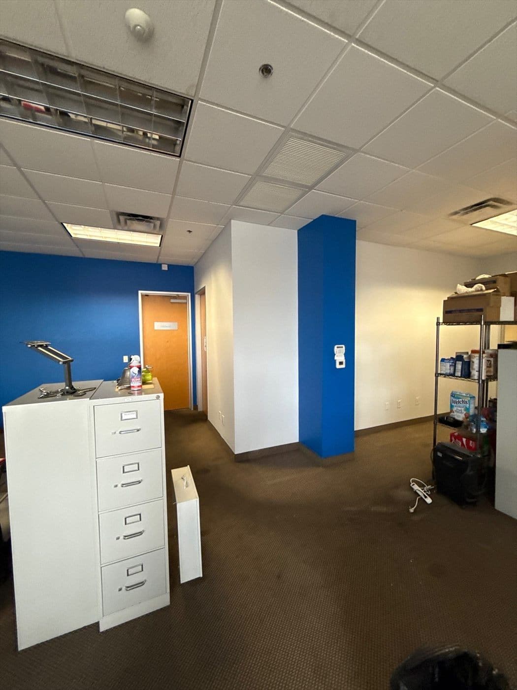 Open office with white walls and blue accent column near filing cabinets.