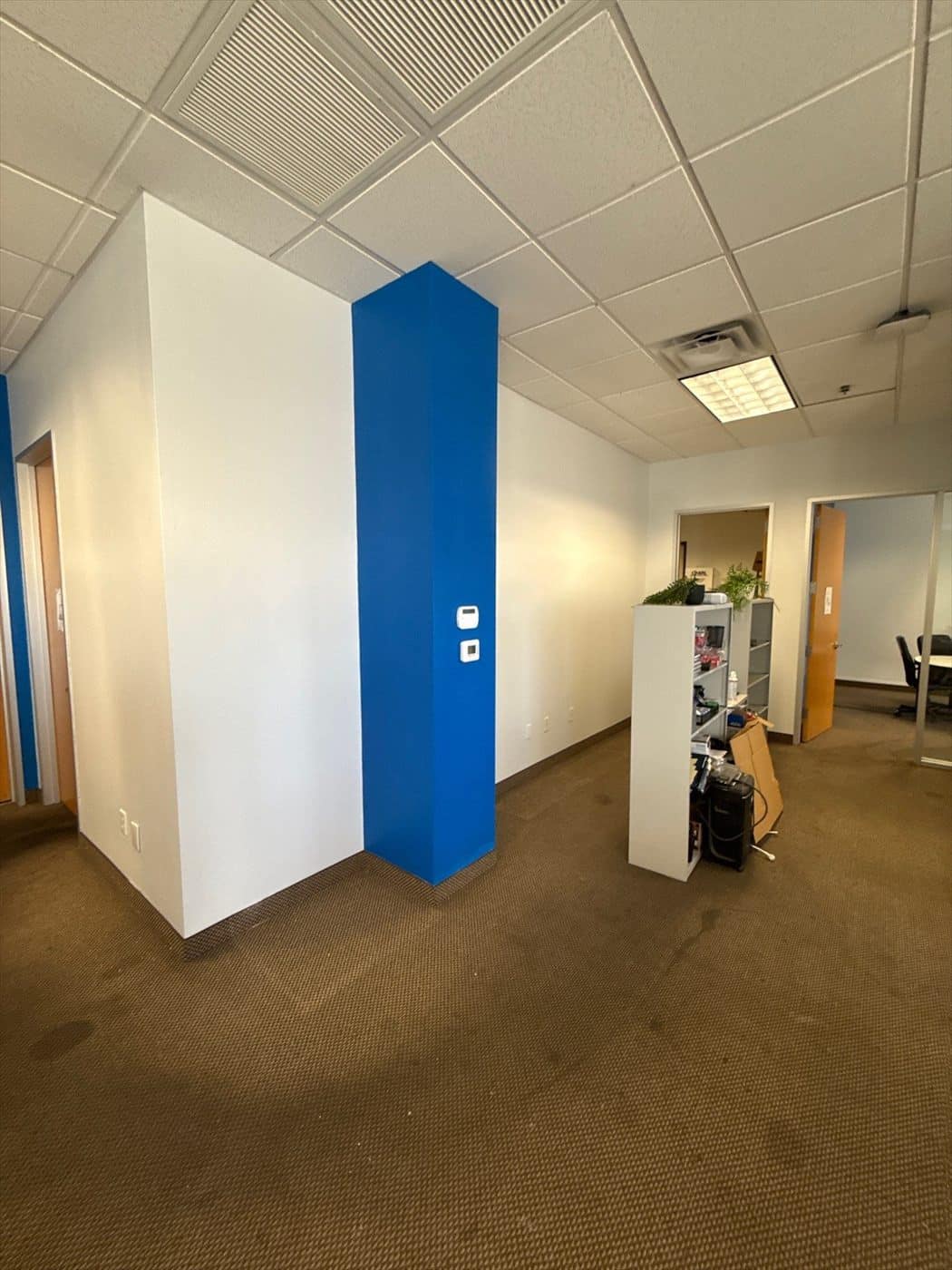 Painted white wall with a blue accent column in an open office area.