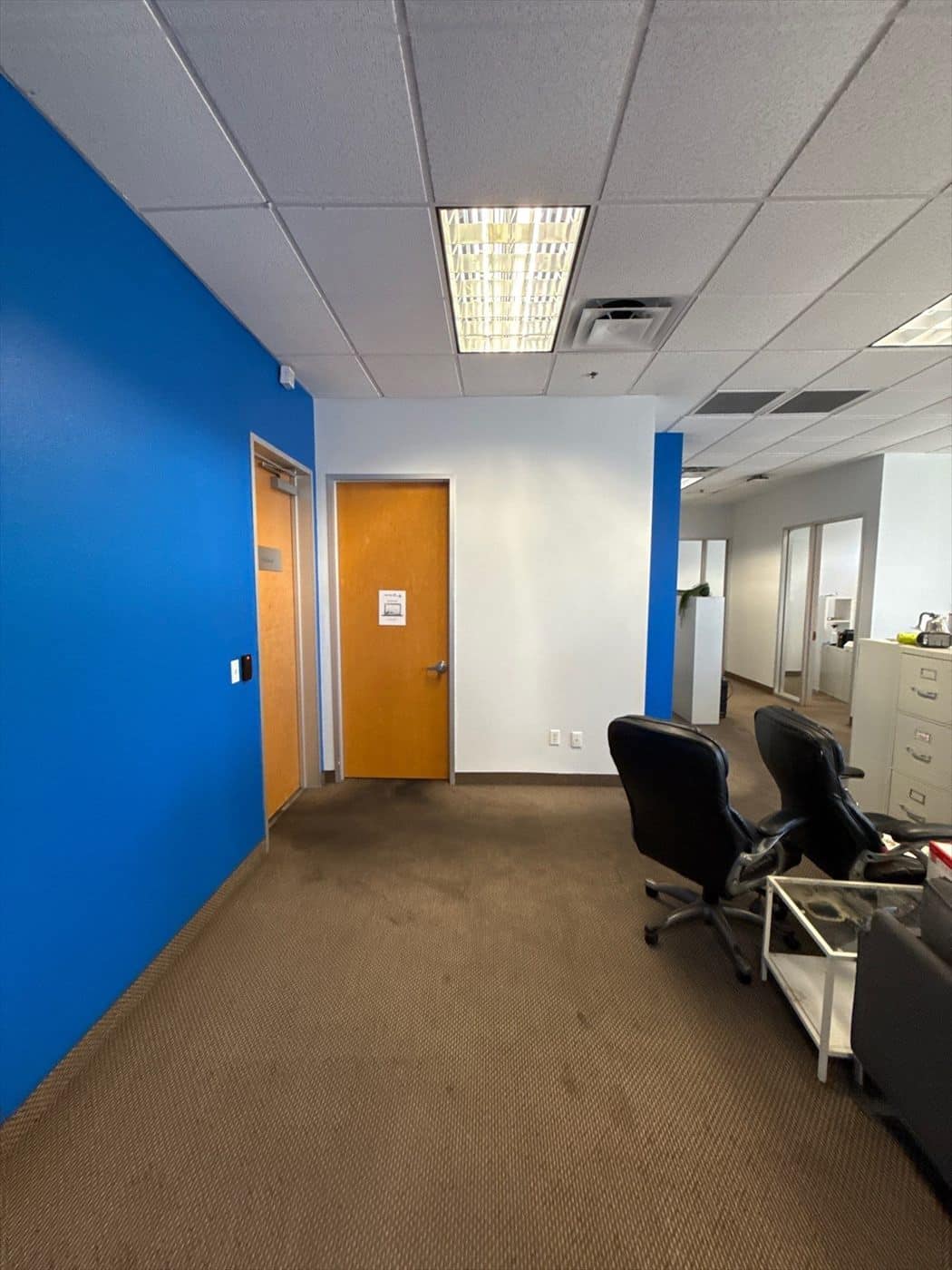 Finished office with blue walls and a wood door alongside office chairs.