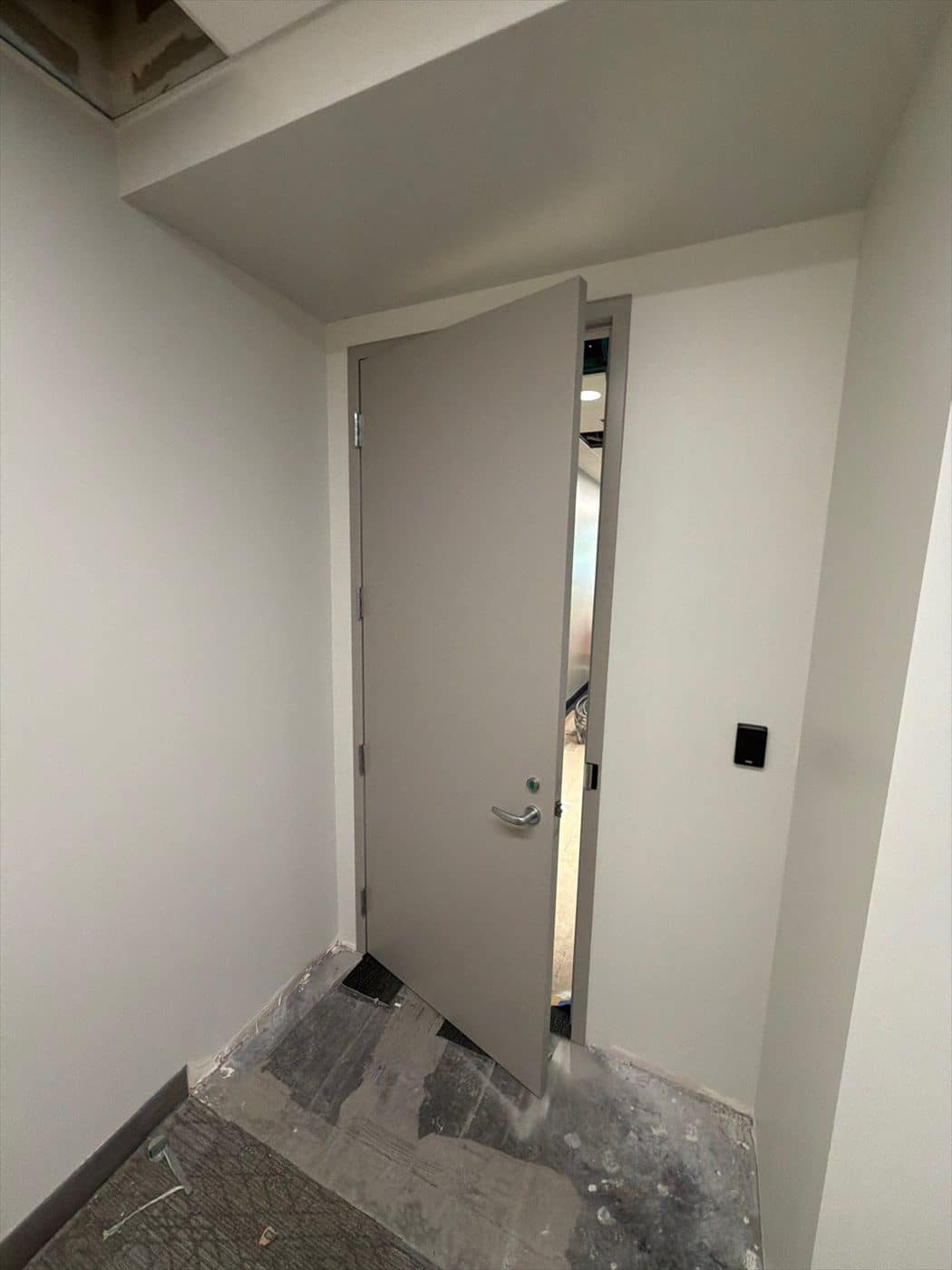 Finished gray door and frame in a small painted vestibule with tile floor.