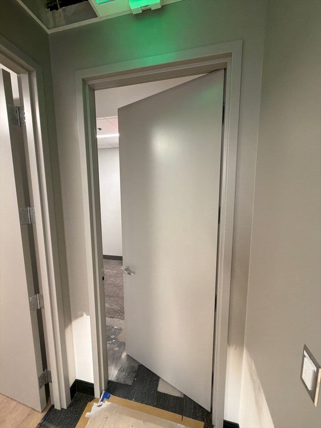 Completed interior door and frame with green exit light glowing above.