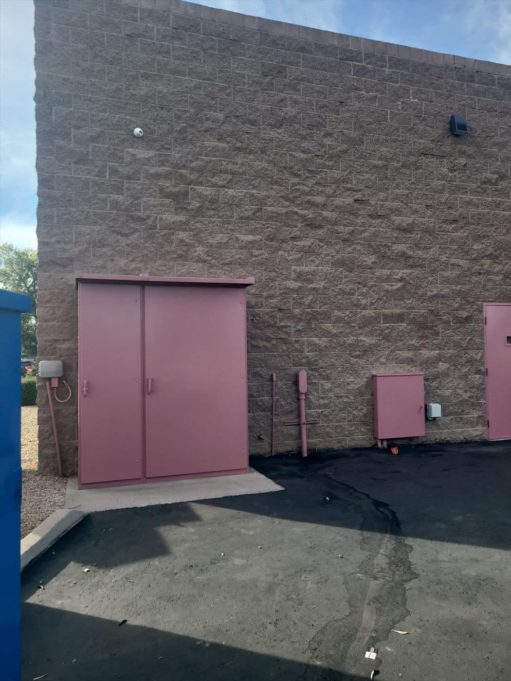 Pink painted electrical equipment enclosure against a split-face block wall.