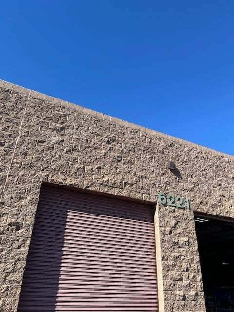 Split-face block warehouse wall with a mauve rolling door and address number 6221.