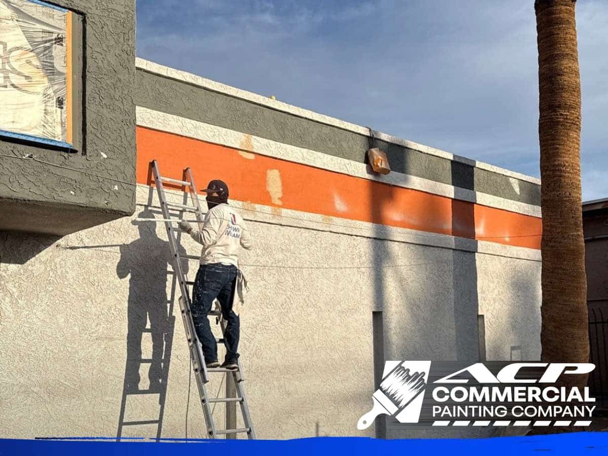 Painter on a ladder repainting a commercial building exterior in Arizona, ACP Commercial Painting Company